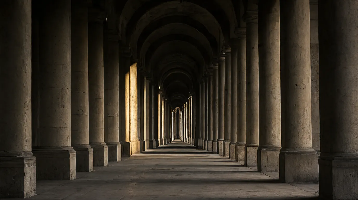 A long stone colonnade, one column caught in a single shaft of light.